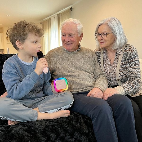 Grandparents and grandson singing with an IROO karaoke machine